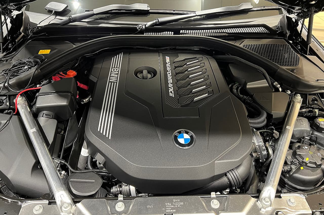 BMW B58 engine bay showing black plastic engine cover with BMW logo, white striping, and surrounding automotive components