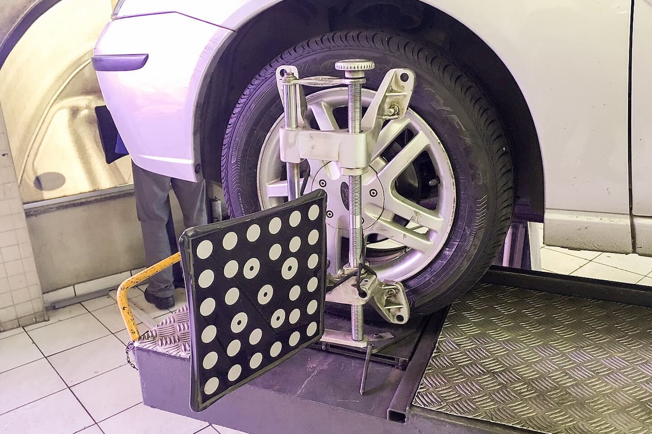 Car wheel attached to professional wheel alignment machine with dotted calibration panel in automotive service garage