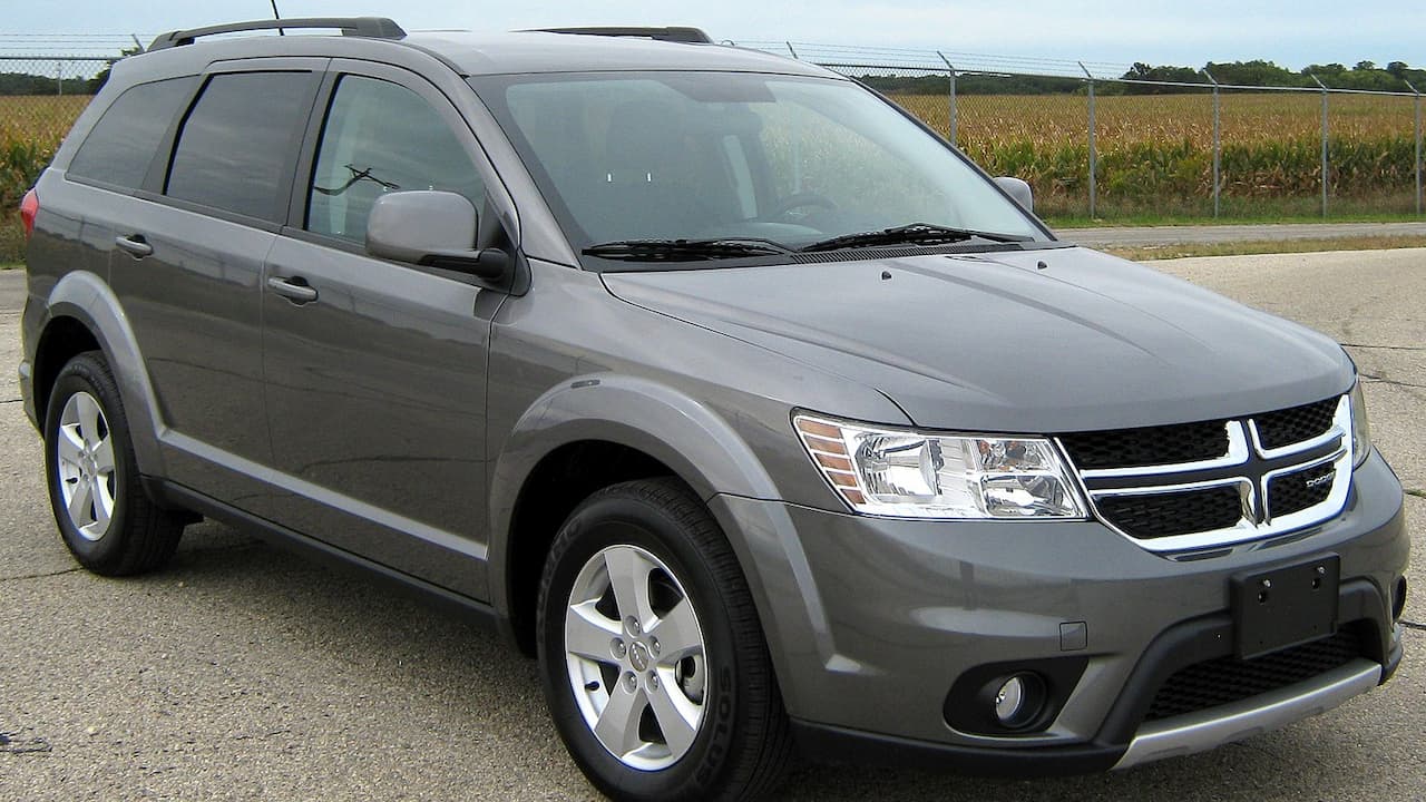 Gray Dodge Journey SUV parked on pavement with chrome grille, alloy wheels, and rural farmland visible in background