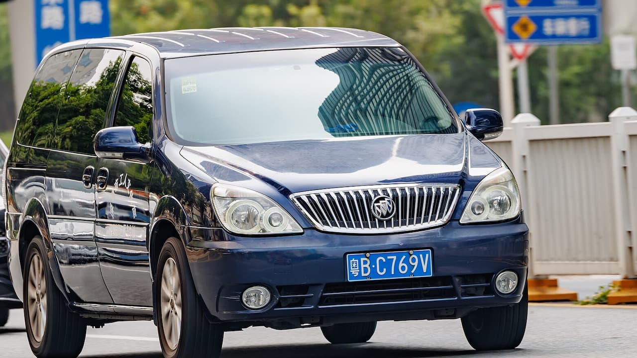 Dark blue 2022 Buick GL8 minivan with chrome grille and Chinese license plate driving on city street