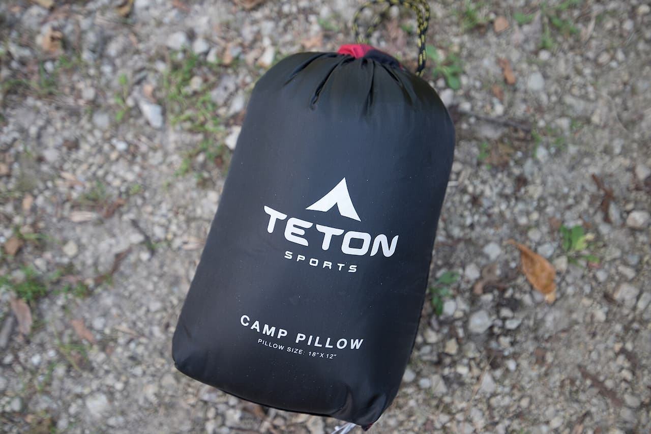 Black Teton Sports camp pillow in compression stuff sack with drawstring closure on rocky ground with fallen leaves