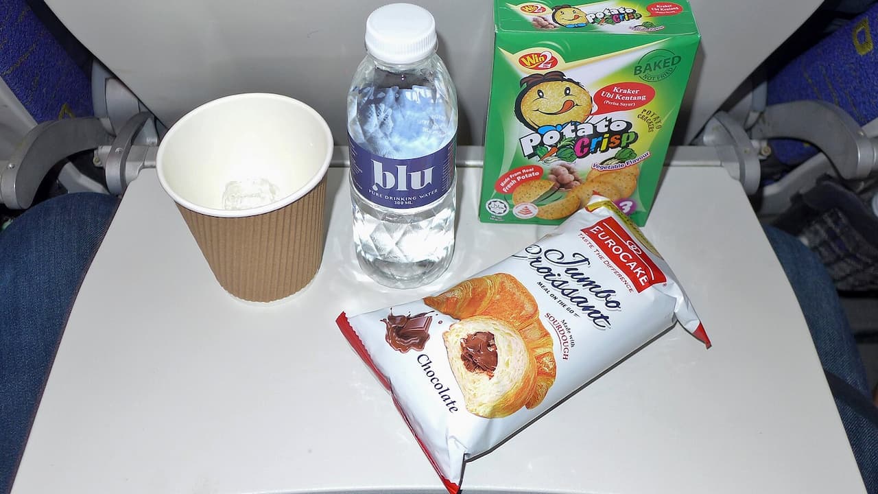 Tray with bottled water, coffee cup, chocolate croissant package, and potato crisps box snacks