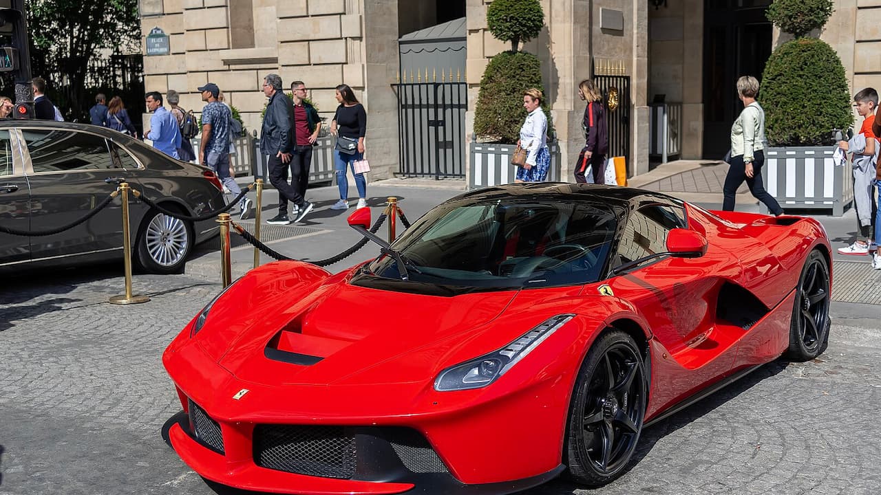 Red Ferrari LaFerrari supercar with black accents displayed on cobblestone street surrounded by spectators and barriers