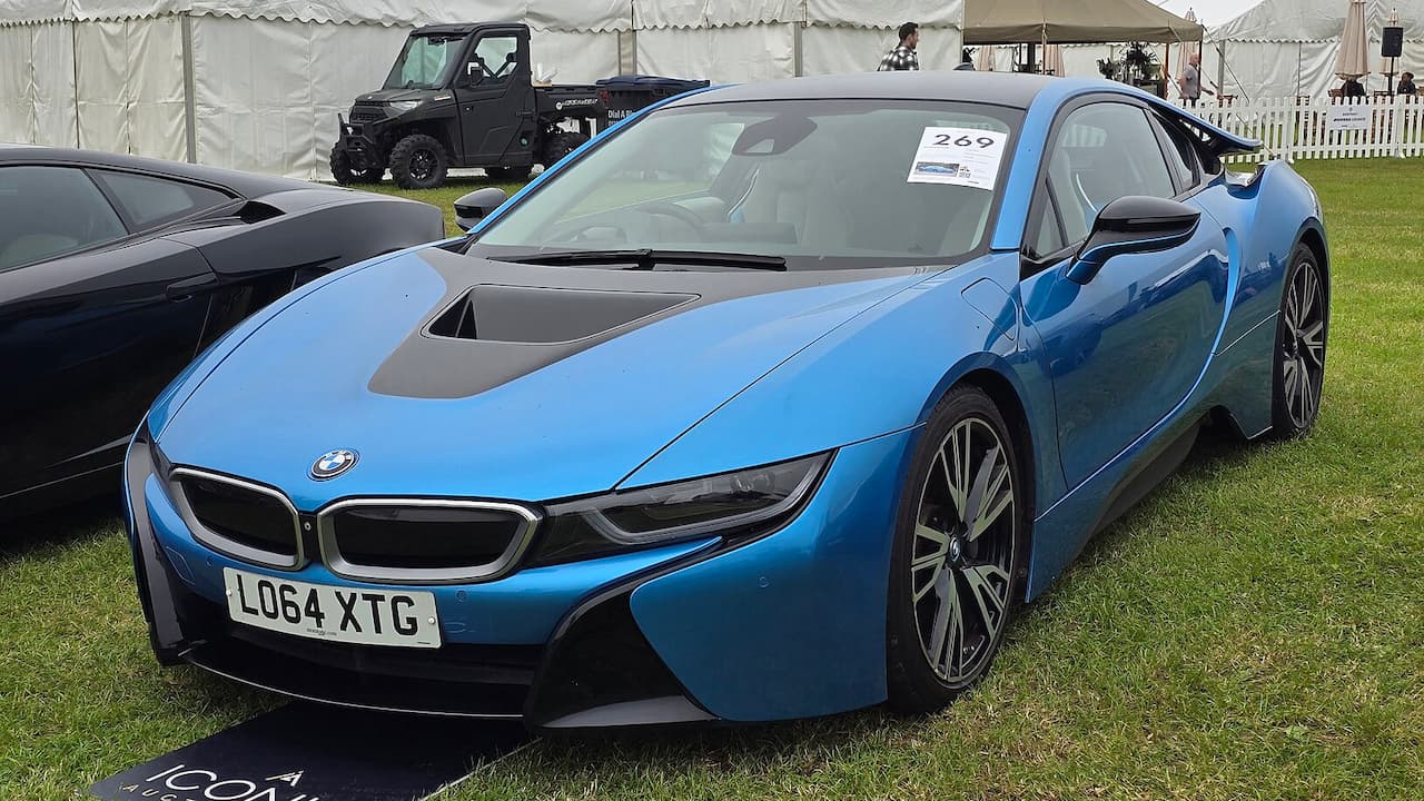 Blue BMW i8 with distinctive design and UK license plate at outdoor car show