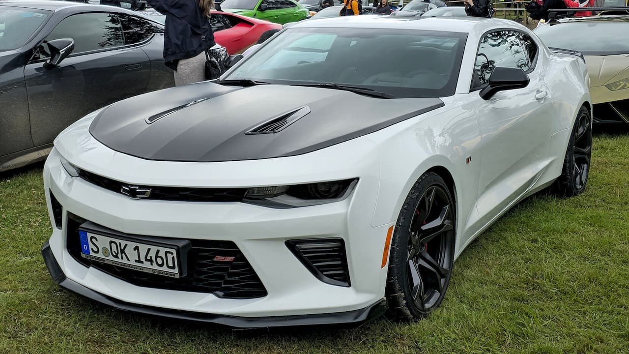 White Chevrolet Camaro SS with black hood stripes and dark wheels at outdoor car show