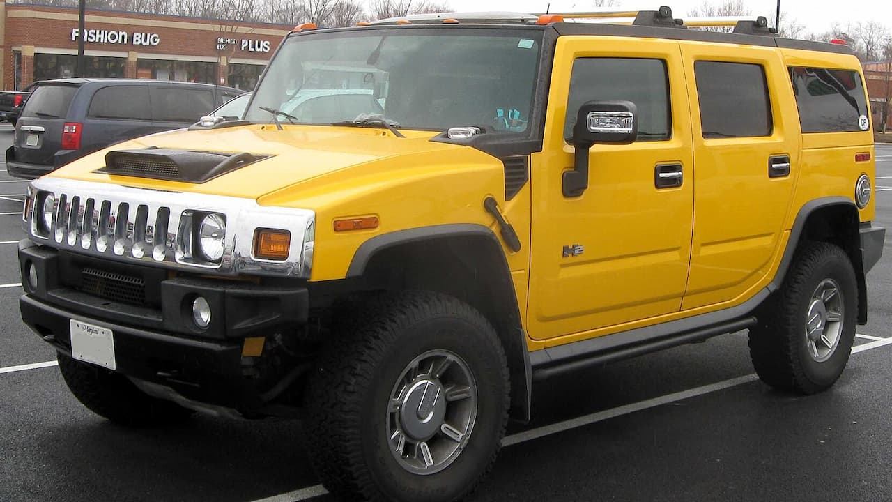Yellow Hummer H2 SUV with chrome grille and alloy wheels parked in shopping center parking lot
