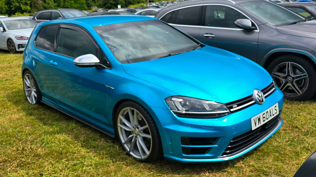 Bright blue Volkswagen Golf R hot hatch with sporty wheels and UK license plate at car show