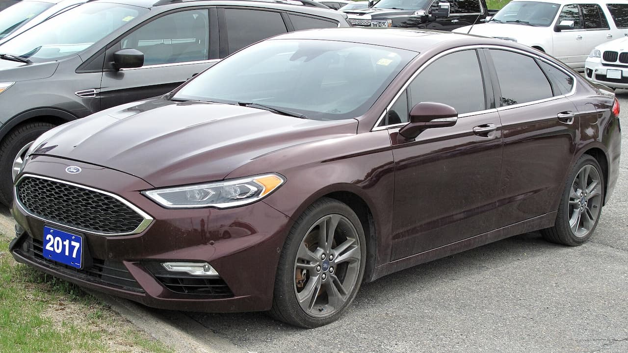 Burgundy 2017 Ford Fusion Sport sedan with honeycomb grille and alloy wheels parked in lot with other vehicles