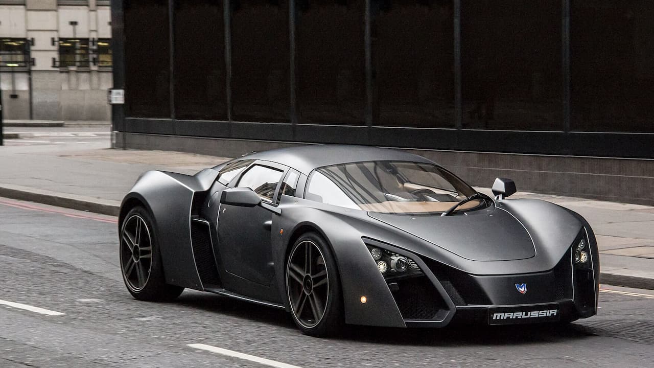 Dark gray Marussia B2 supercar with angular design and large wheels parked on urban street