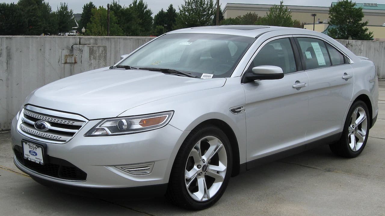 Silver Ford Taurus SHO sedan with chrome grille and alloy wheels parked on concrete near concrete barriers