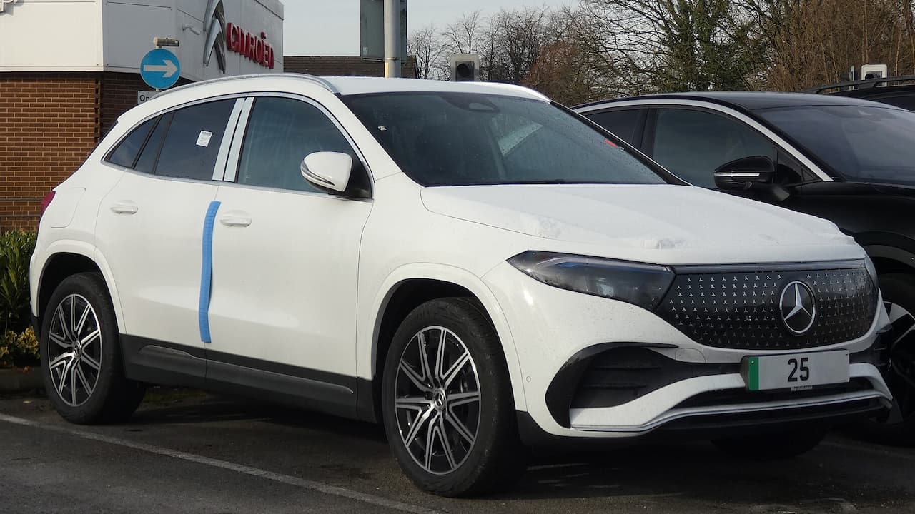 White 2025 Mercedes-Benz EQA electric SUV parked in dealership lot with distinctive grille and blue accent stripe