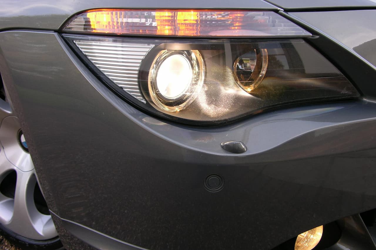 Close-up of modern car headlight with dual circular LED elements, amber turn signal, and gray vehicle body panel