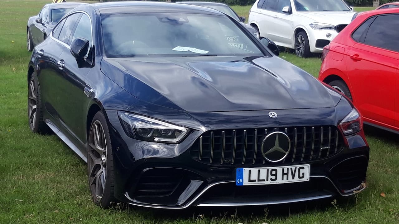 Black Mercedes-AMG GT63 S with distinctive front grille and UK license plate parked on grass