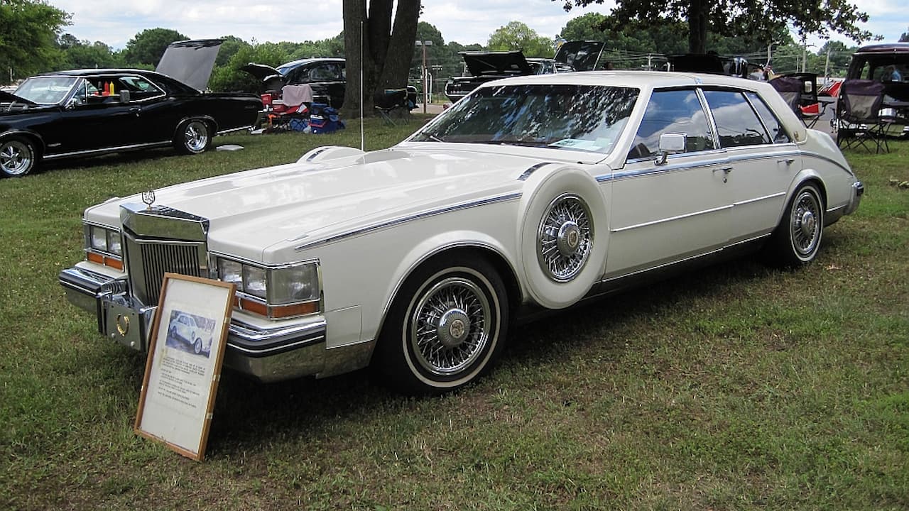White vintage Cadillac luxury car with wire spoke wheels and continental spare tire displayed at outdoor car show