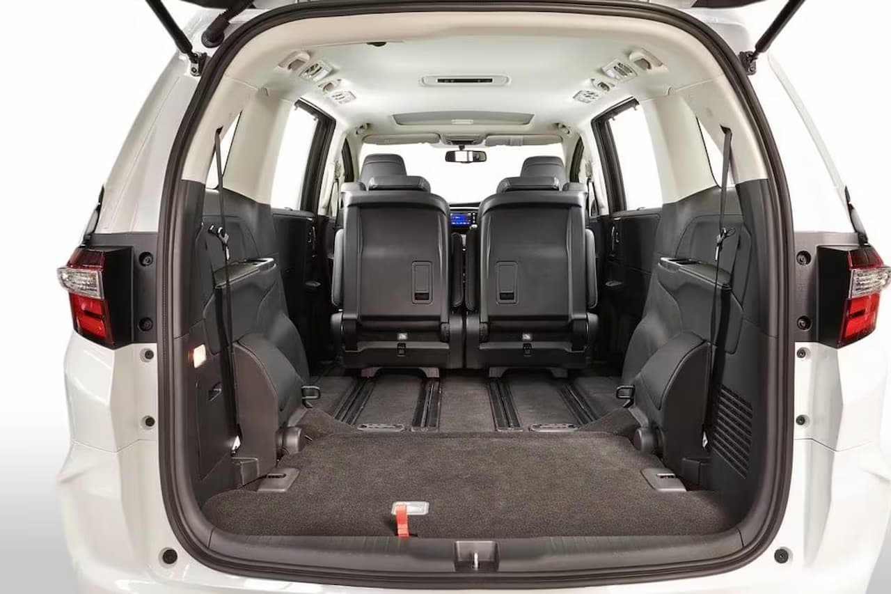 Honda Odyssey minivan interior showing spacious cargo area with folded third-row seats and gray carpet flooring from rear view