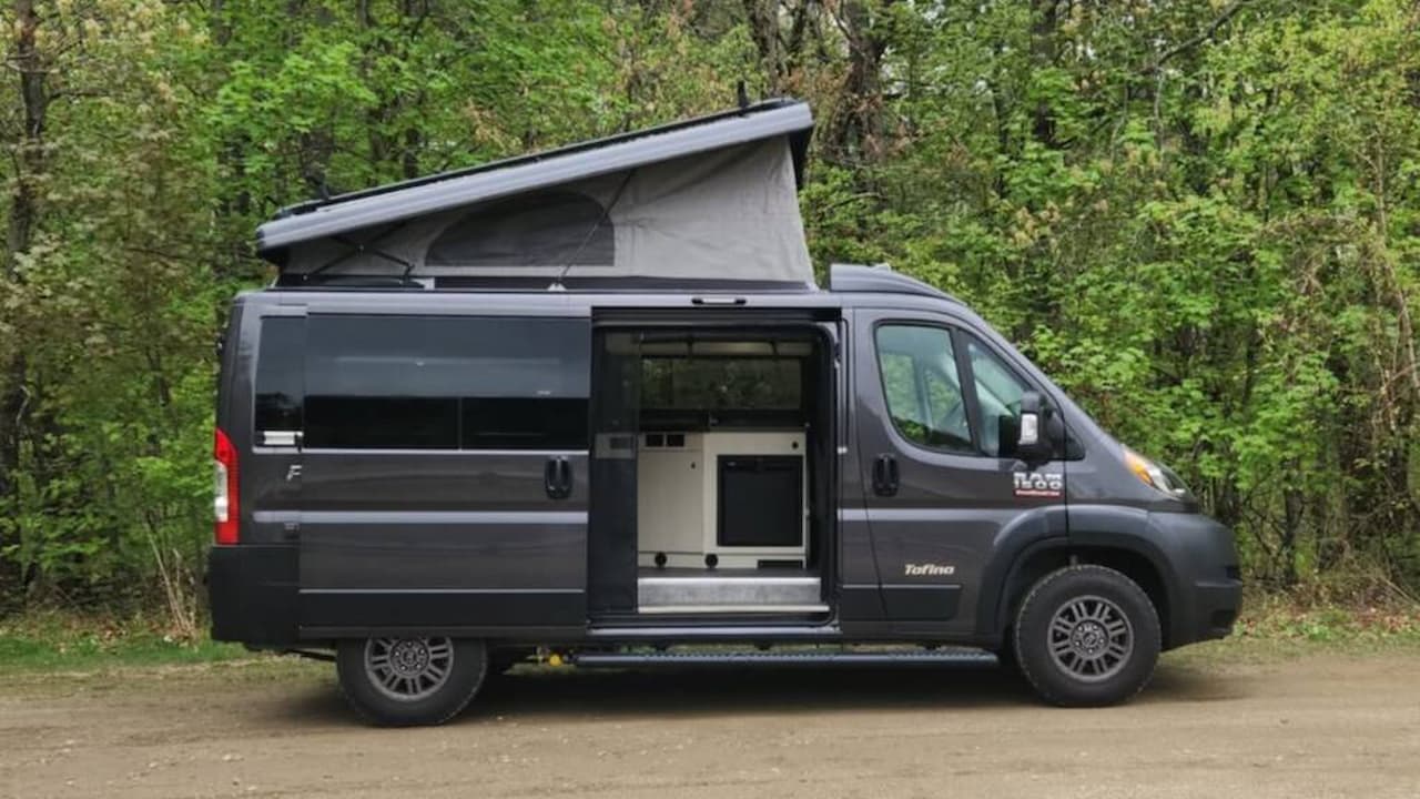 White Oliver Legacy Elite II travel trailer with couple sitting outside under awning in mountain landscape setting