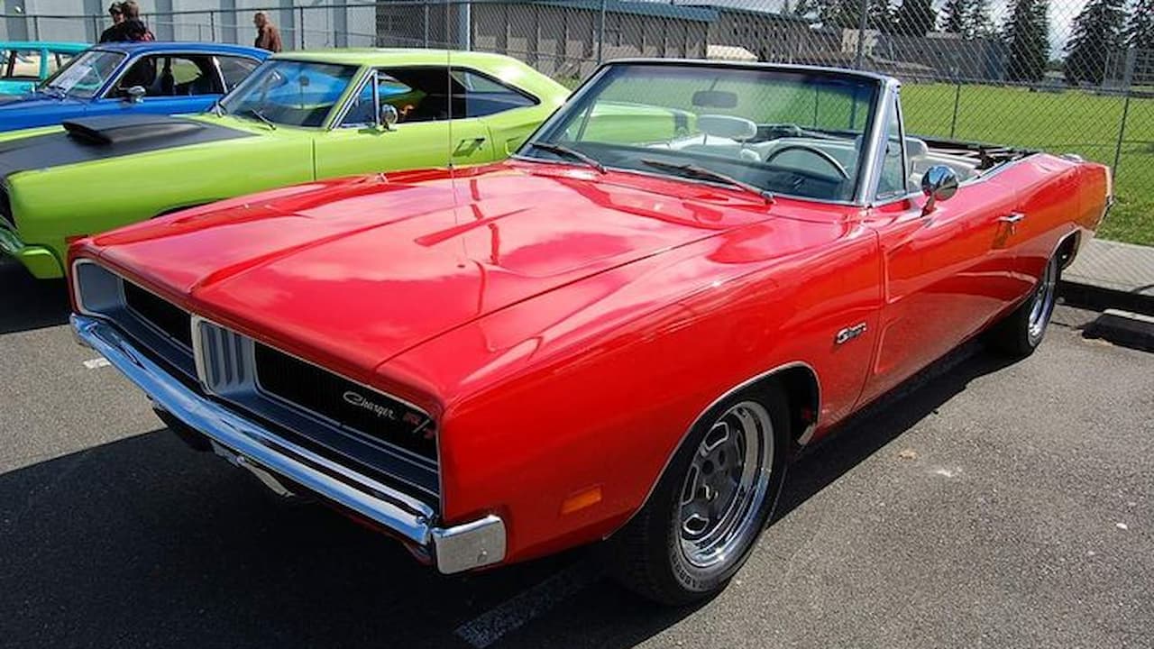 Red 1969 Dodge Charger R/T convertible with black interior parked at car show with other classic vehicles nearby