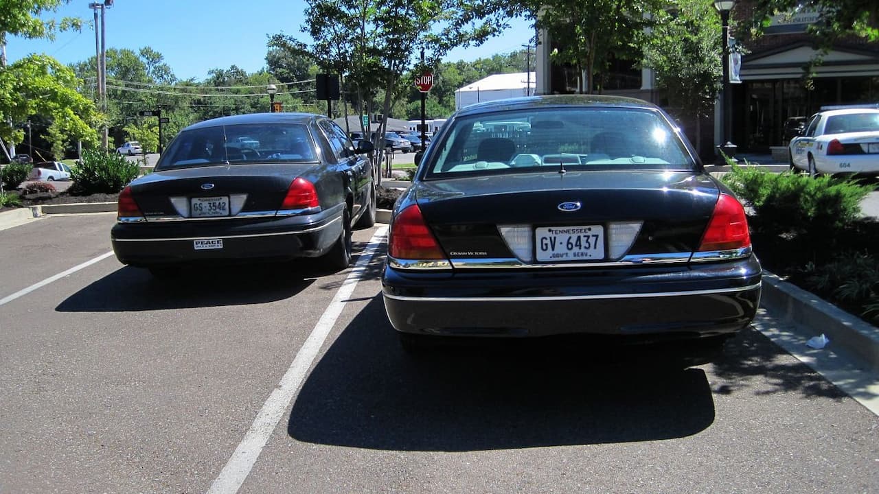 Two black Ford Crown Victoria police cruisers parked in a lot with Tennessee license plates and police equipment visible