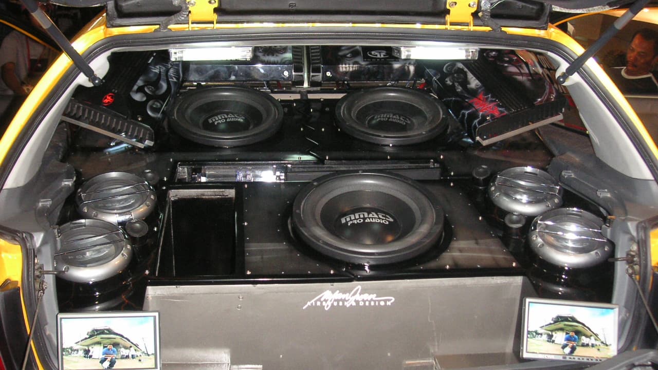 Car trunk with custom audio system featuring multiple large subwoofers, amplifiers, and speakers in organized installation setup