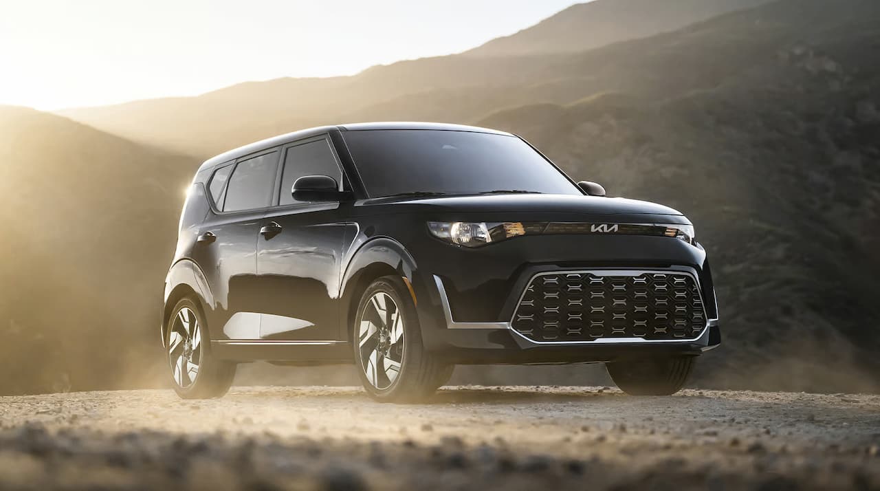 Black 2025 Kia Soul EV positioned on desert terrain with mountain backdrop and golden sunset lighting