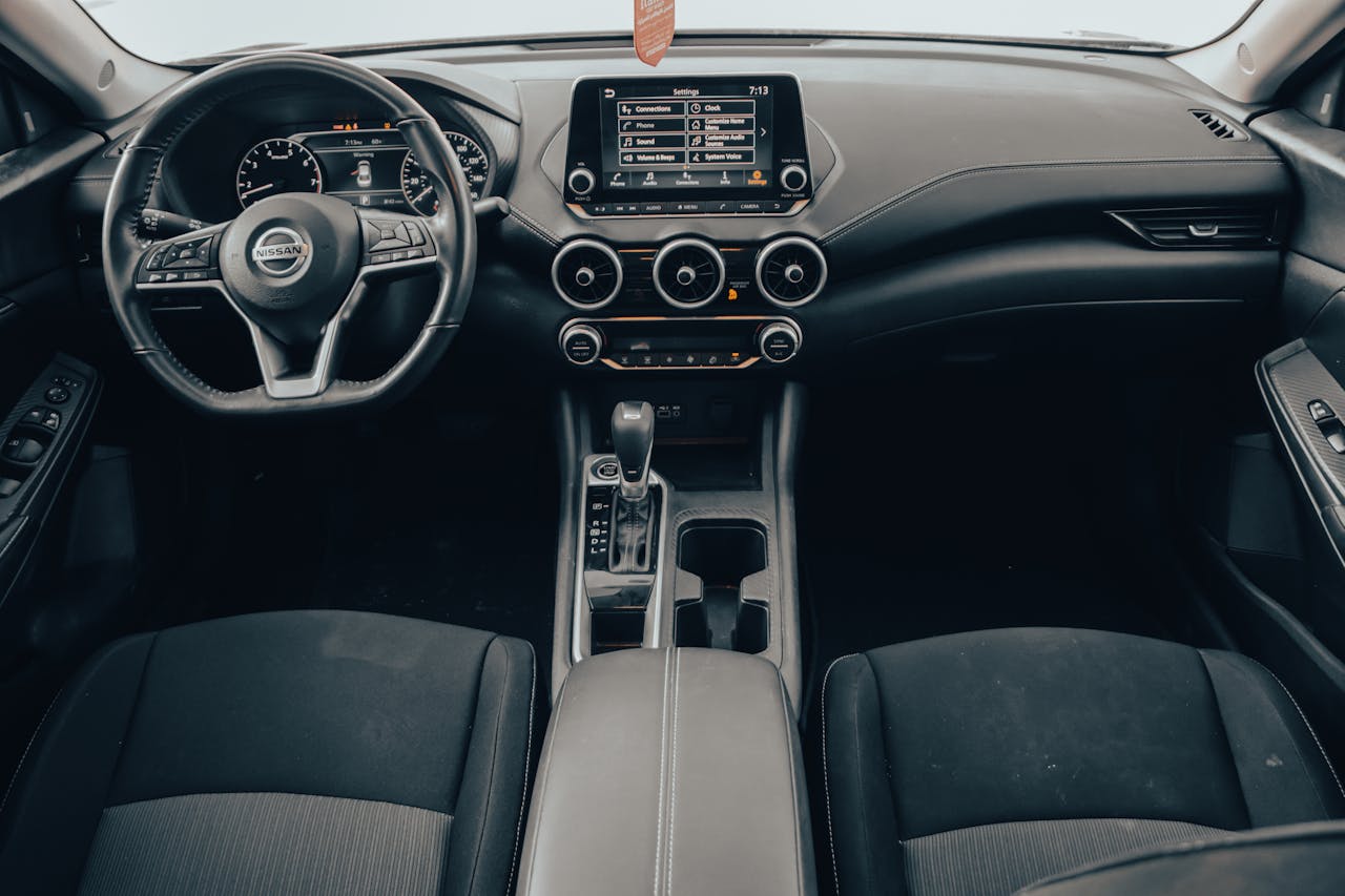 Modern Nissan interior with touchscreen infotainment system, voice-controlled interface, three circular air vents, and automatic transmission shifter