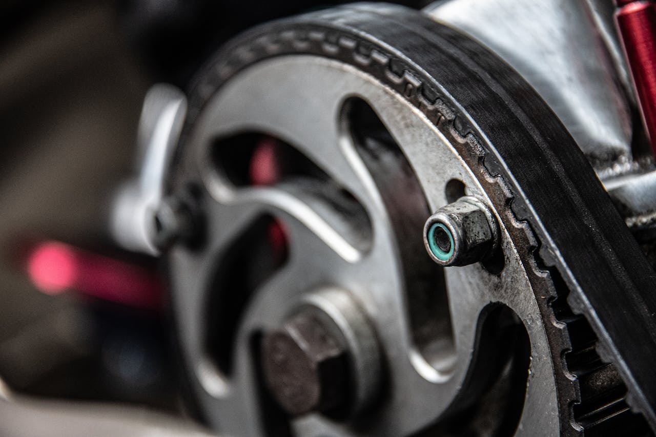 Close-up of automotive timing belt with toothed rubber surface wrapped around metal pulleys in car engine compartment