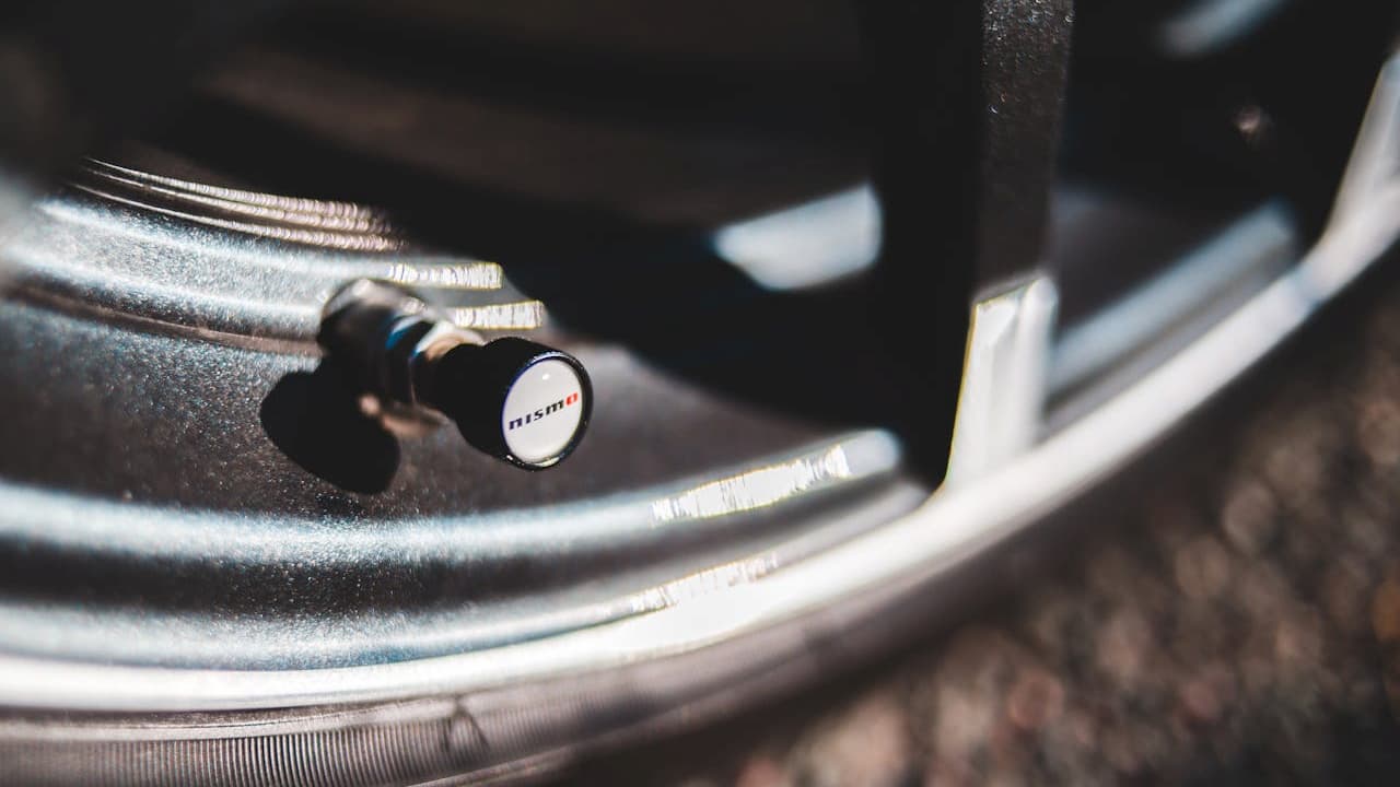 Close-up of NISMO tire pressure monitoring system sensor mounted on silver alloy wheel rim with tire valve