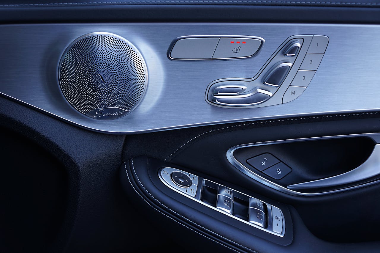 Luxury car door panel featuring Burmester premium audio speaker, seat adjustment controls, window switches, and heated seat buttons