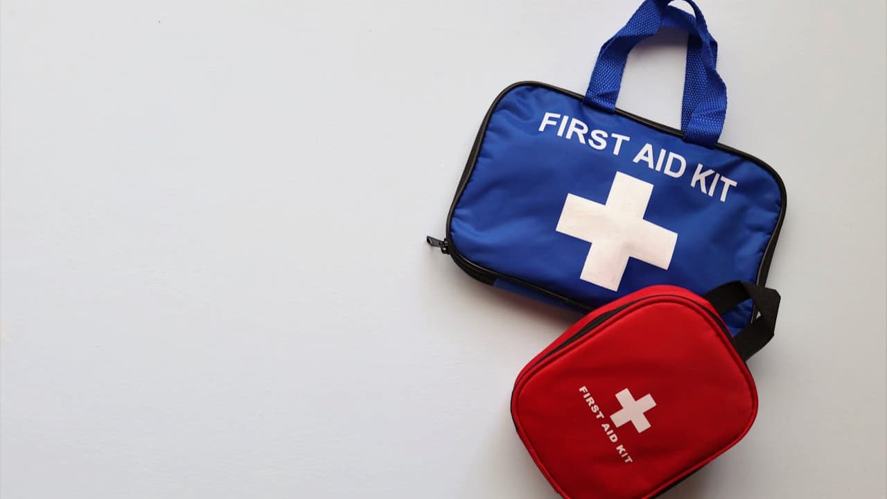 Blue rectangular first aid kit with white cross and red oval first aid kit on white background