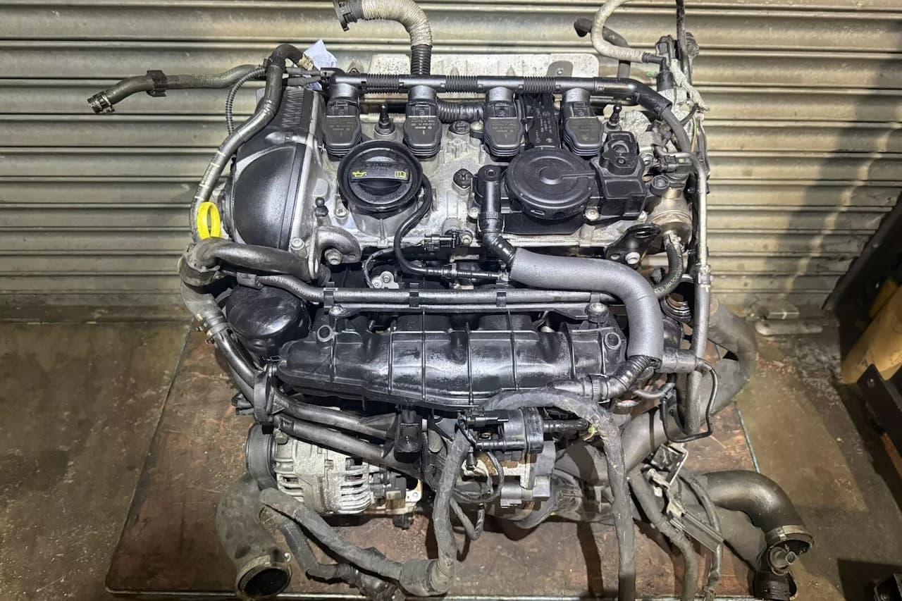 Volkswagen 2.0 TSI engine assembly removed from vehicle, showing turbocharger, intake manifold, fuel injectors, and various hoses on workshop floor