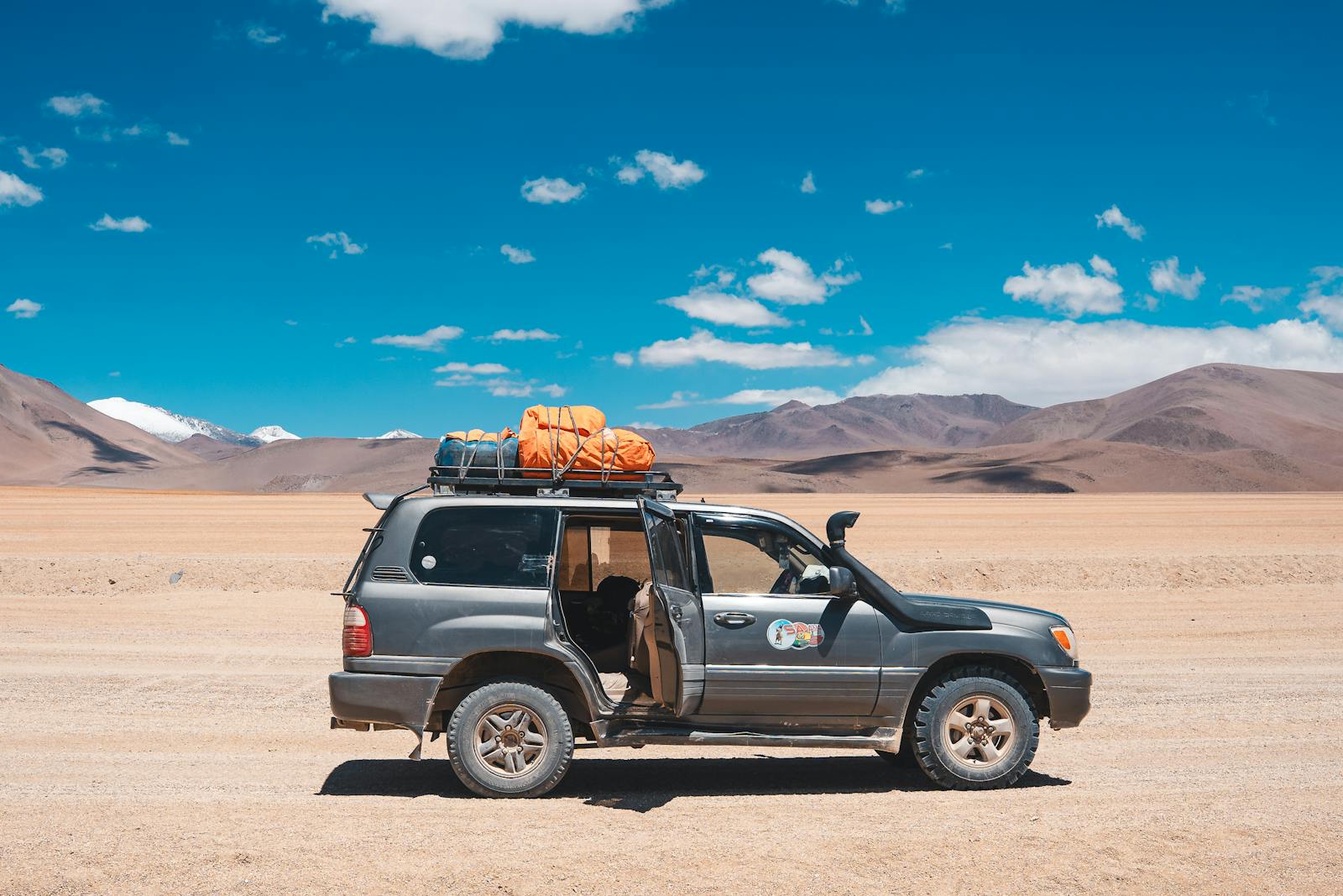 4x4 vehicle in Bolivia's Uyuni Salt Flat surrounded by stunning desert scenery.