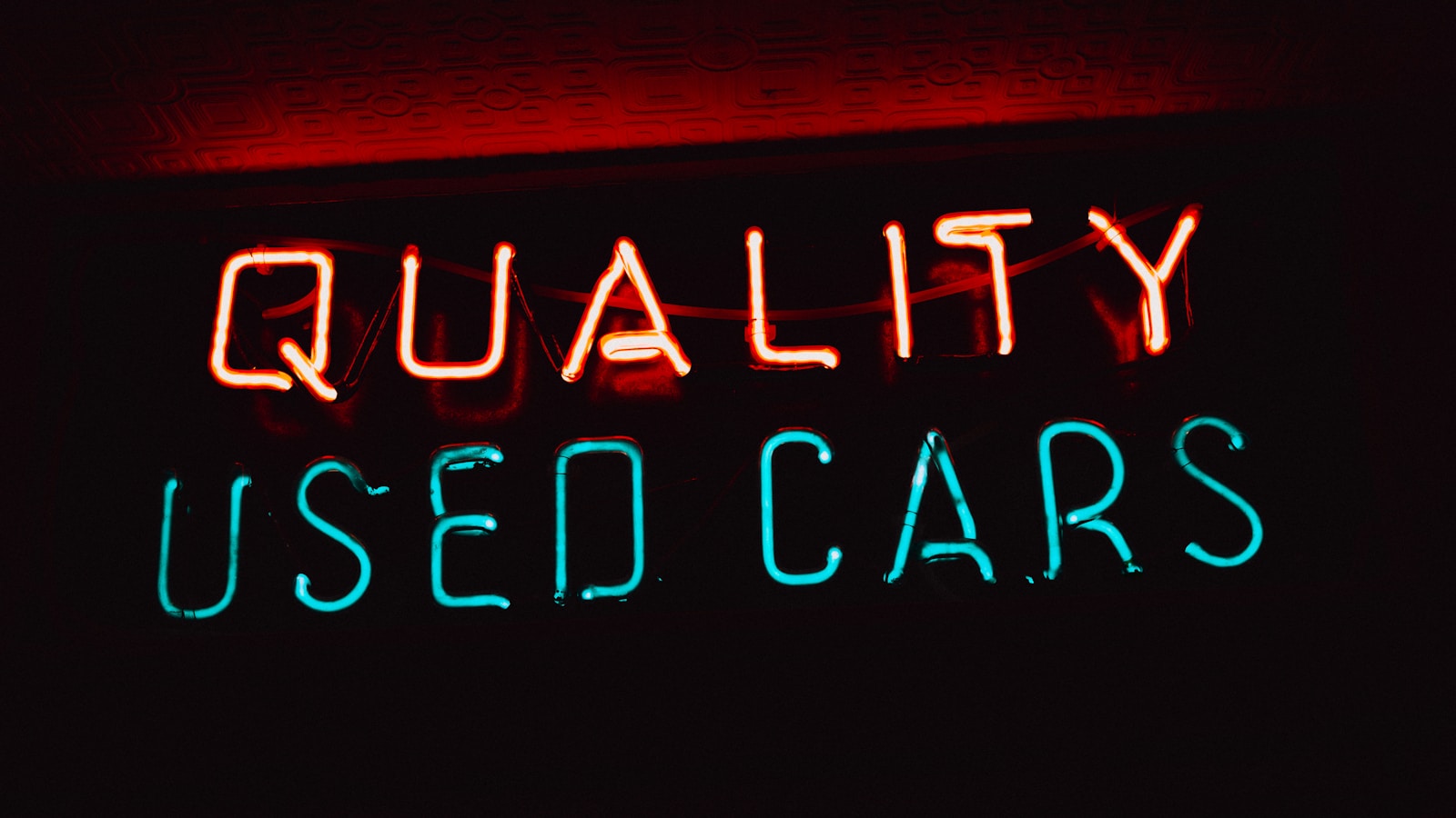 a neon sign that says quality used cars