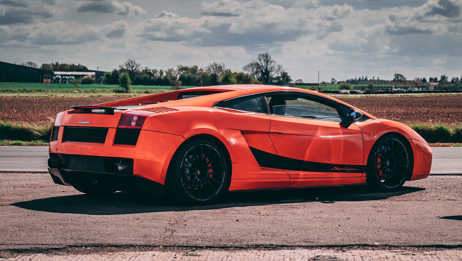 an orange sports car parked on the side of the road
