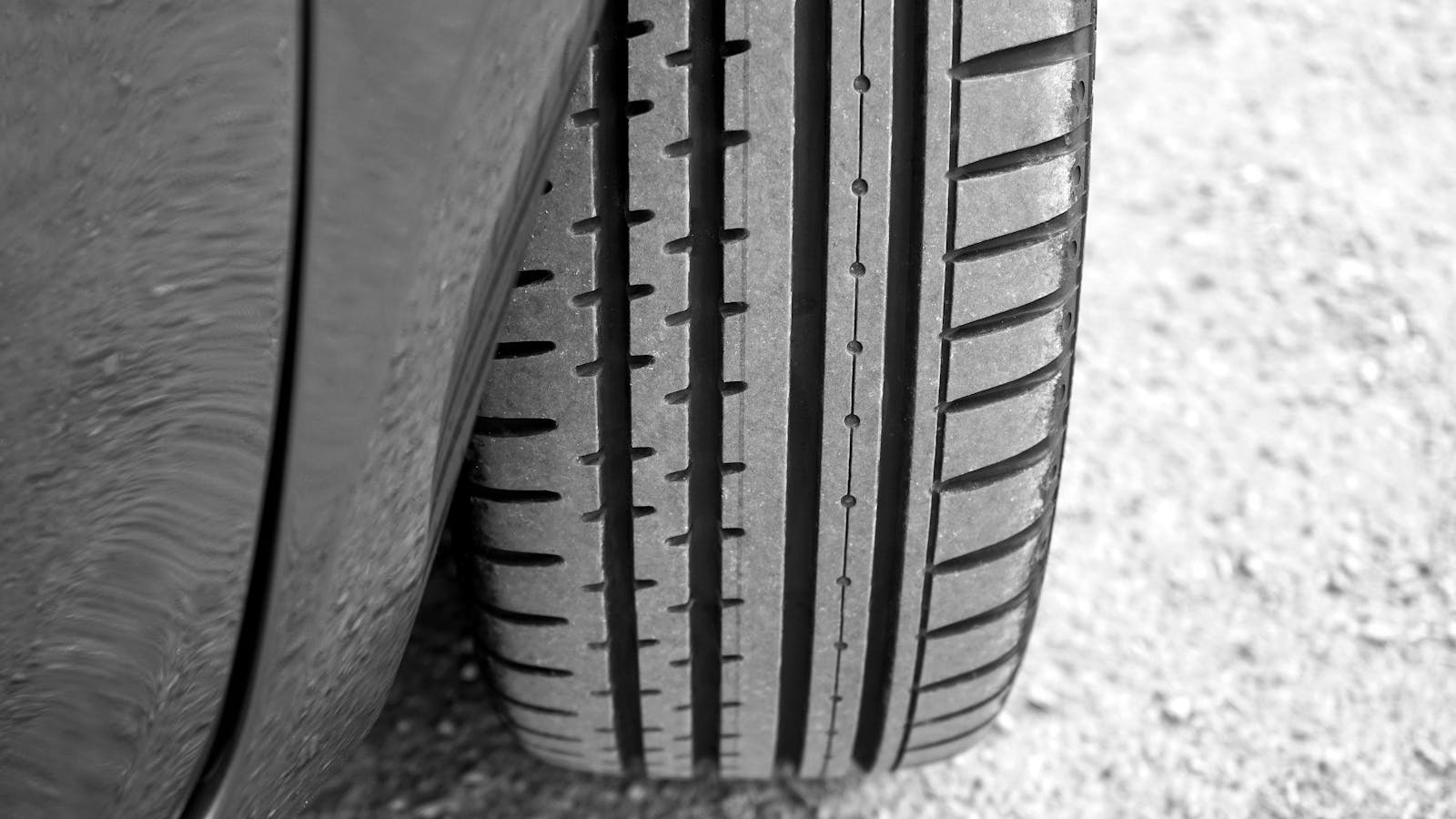 Detailed view of vehicle tire on a gravel surface, showcasing tread pattern.