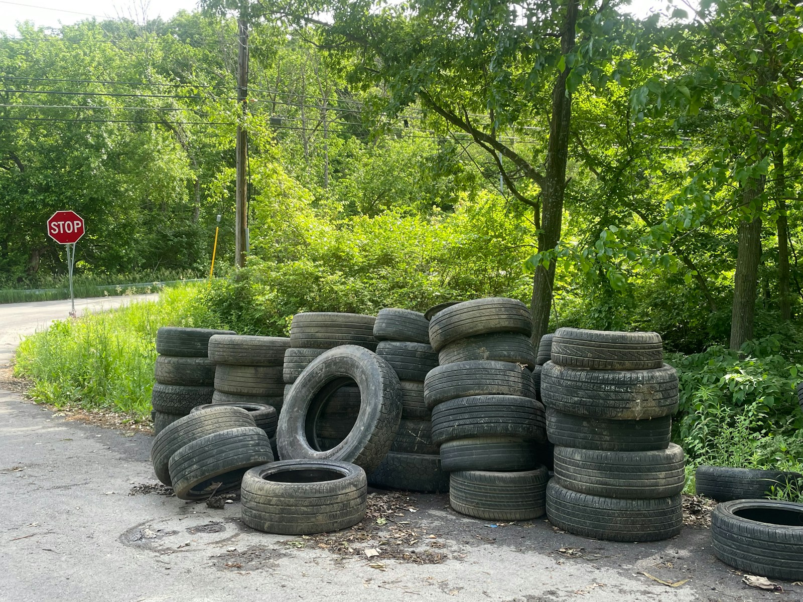 A pile of used tires beside a road.