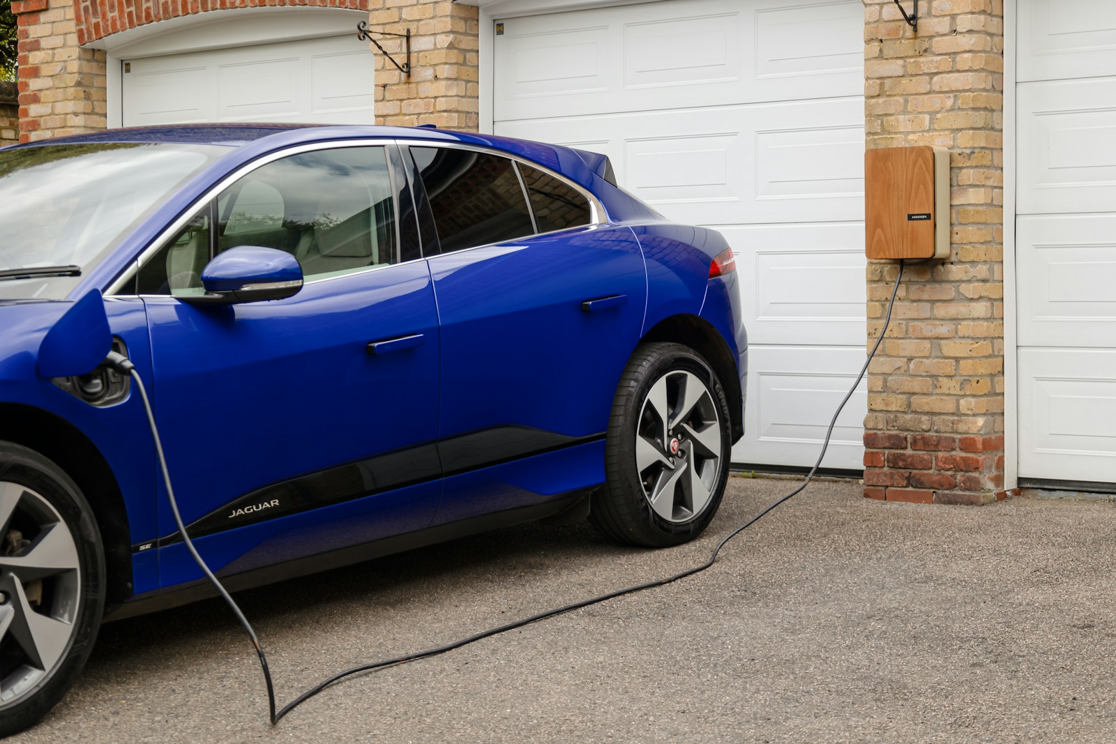A blue electric car plugged in to a garage