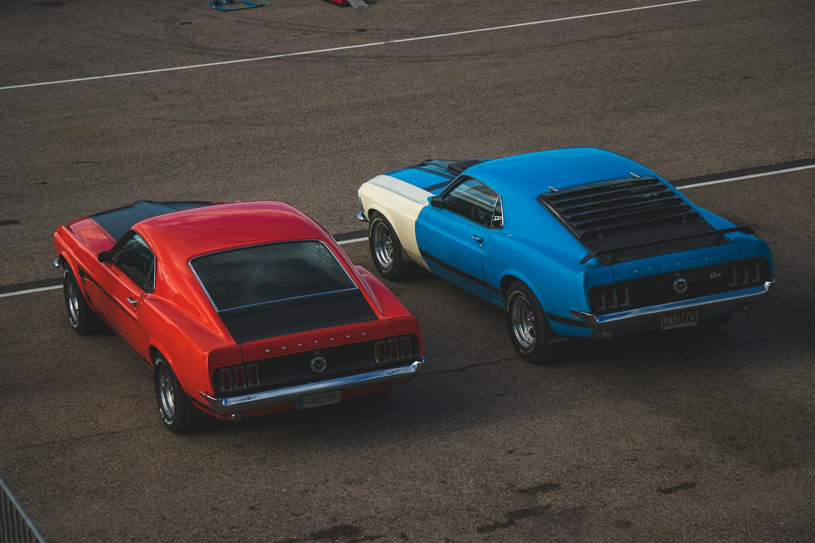 Two vintage Ford Mustangs parked on pavement in an outdoor setting.