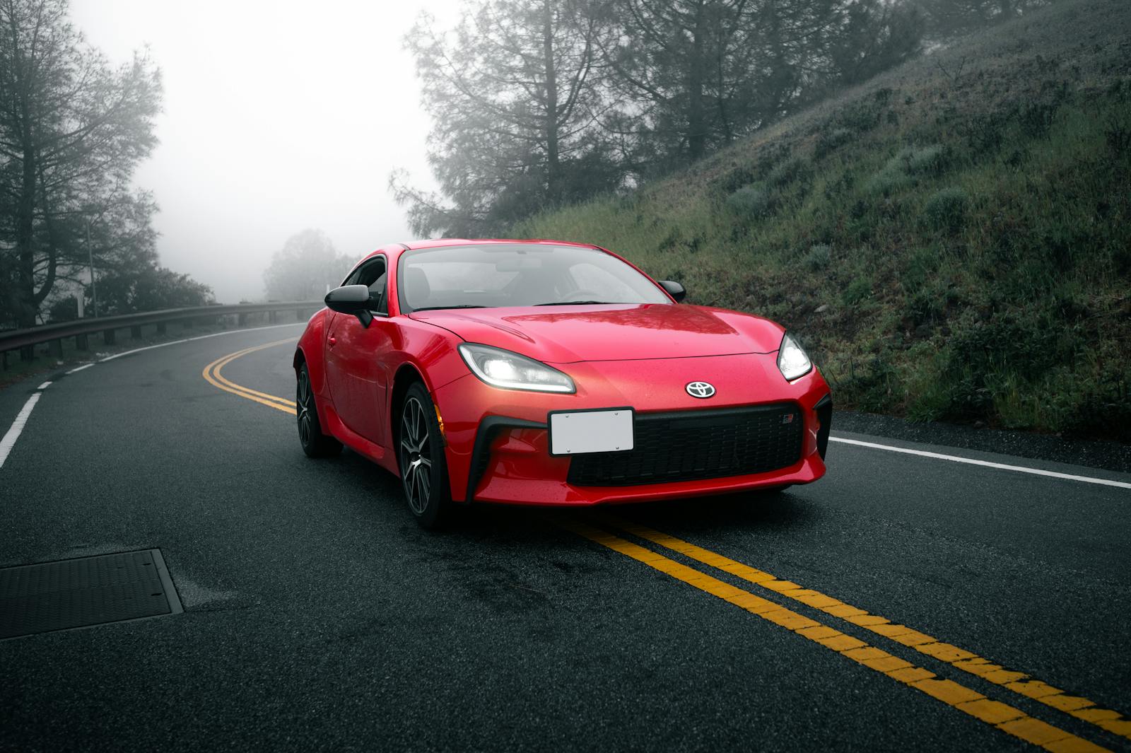 A sleek red sportscar navigating a foggy, winding road in San Jose, California.