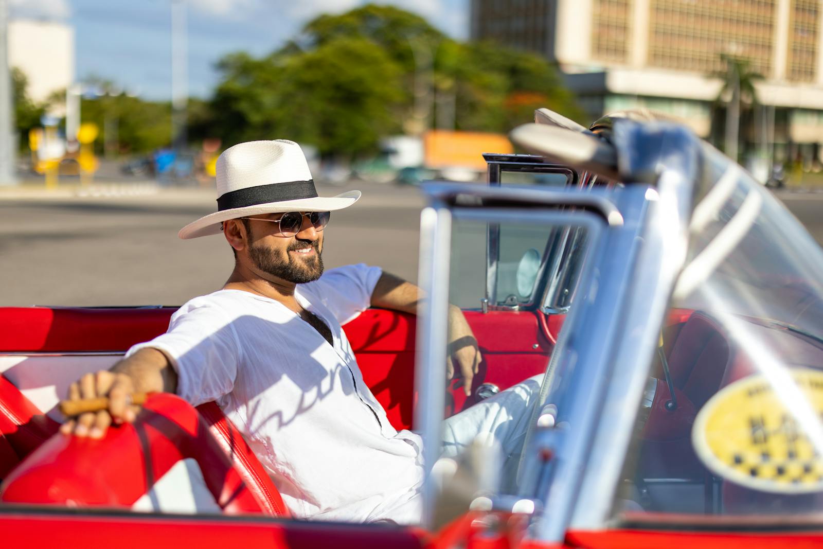 Relaxed man enjoying a sunny day in a classic convertible car on the streets of Havana, Cuba.