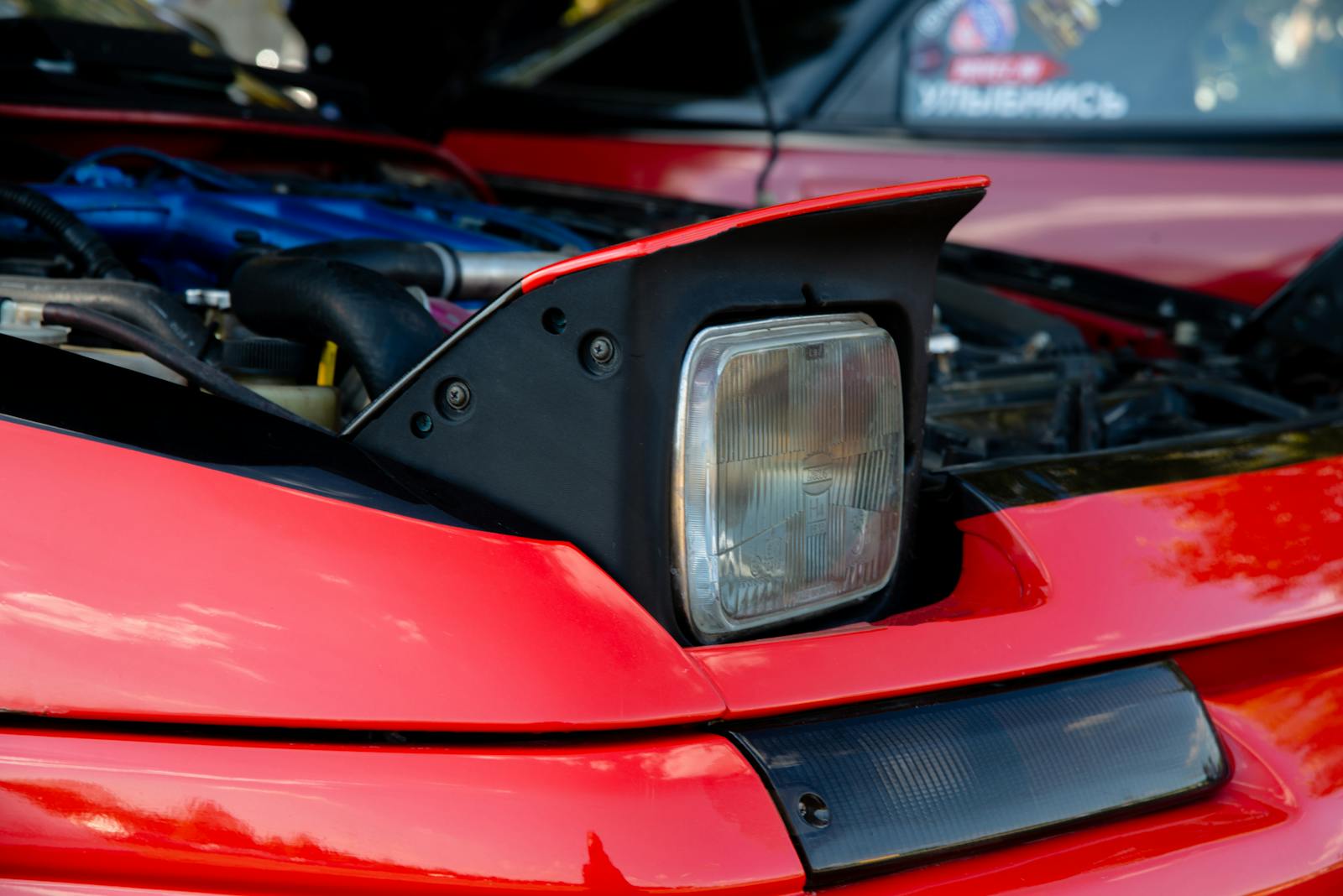 Detailed view of a red sports car with visible engine and pop-up headlight.