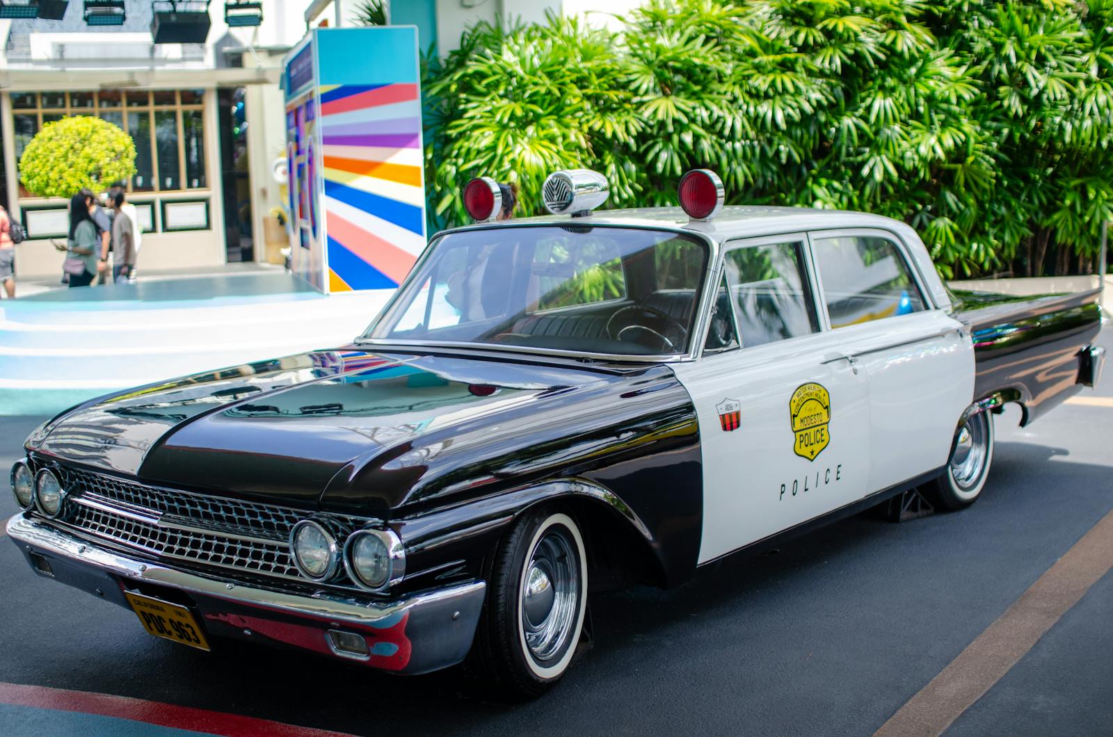 Vintage black and white police car parked outdoors on a sunny day.