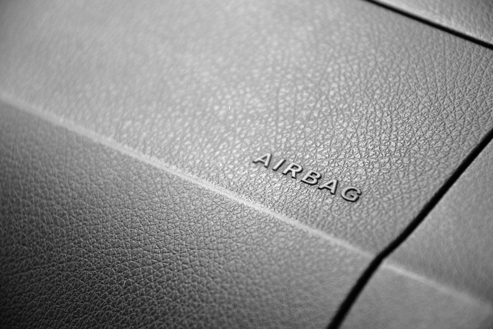 Detailed view of a leather car airbag label on a dashboard in black and white.