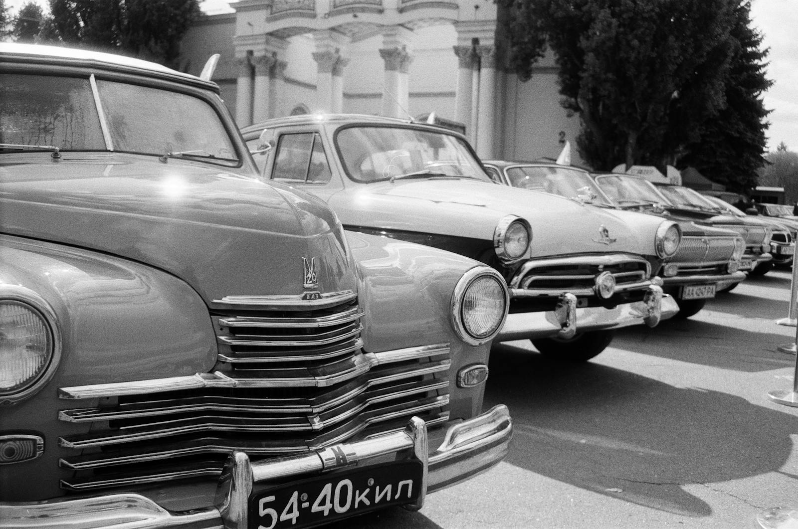 A row of classic vintage cars parked outdoors, showcasing retro automotive design.