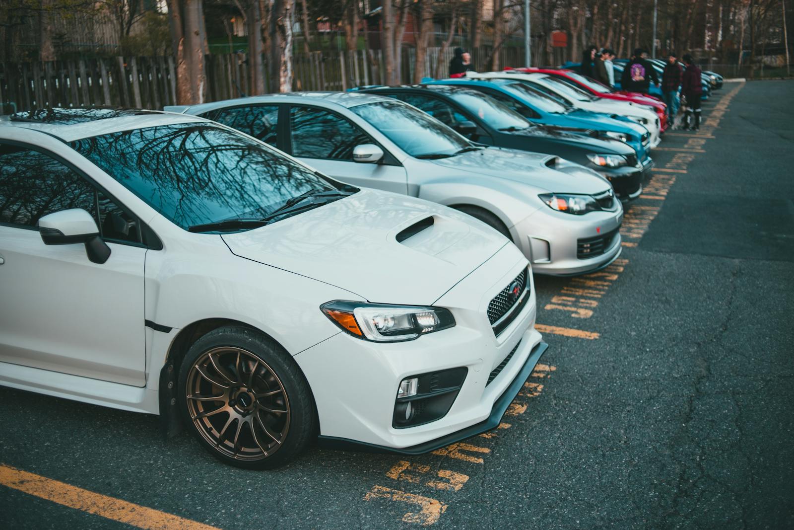 Vibrant lineup of parked cars in an outdoor lot, showcasing various models and colors.