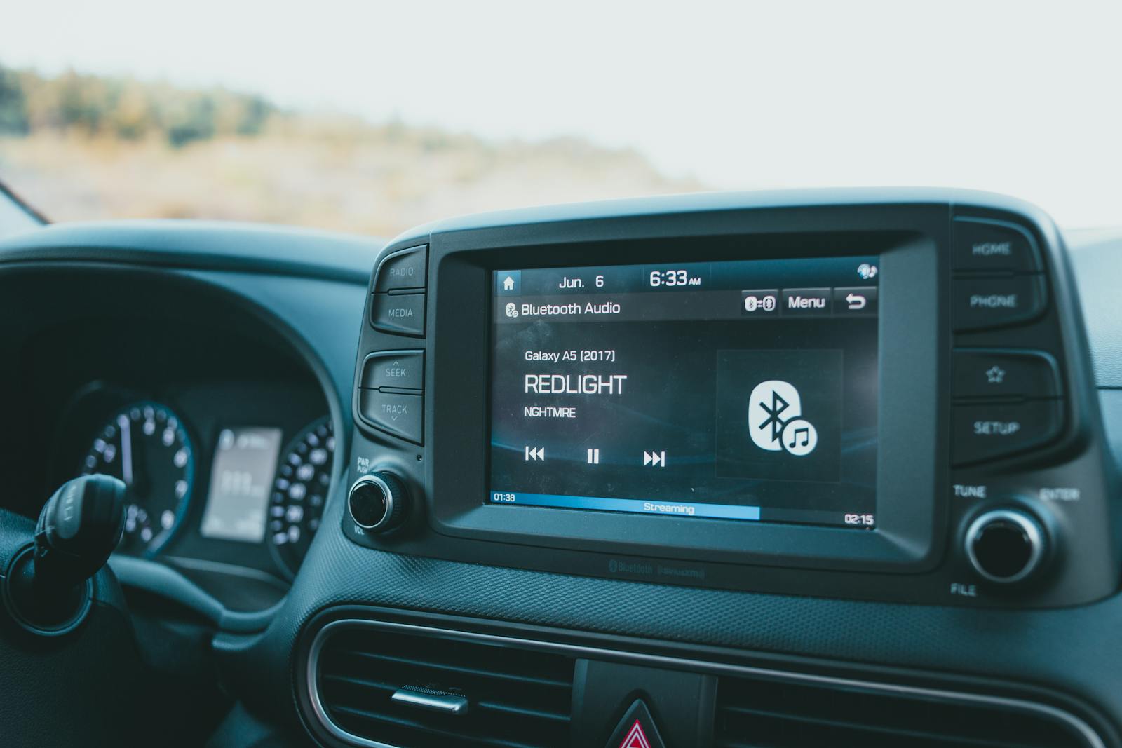 Close-up of a car dashboard featuring a Bluetooth audio system with music display.