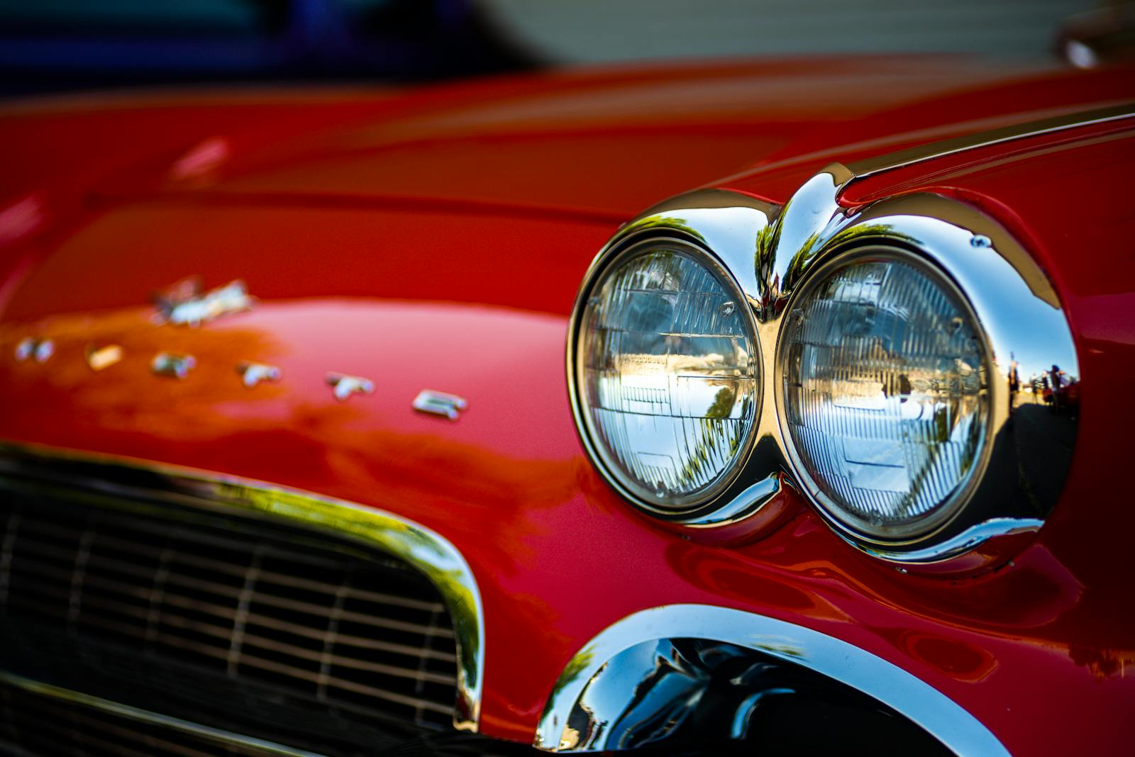Detailed close-up of classic red Corvette car headlights showcasing vintage design and chrome details.