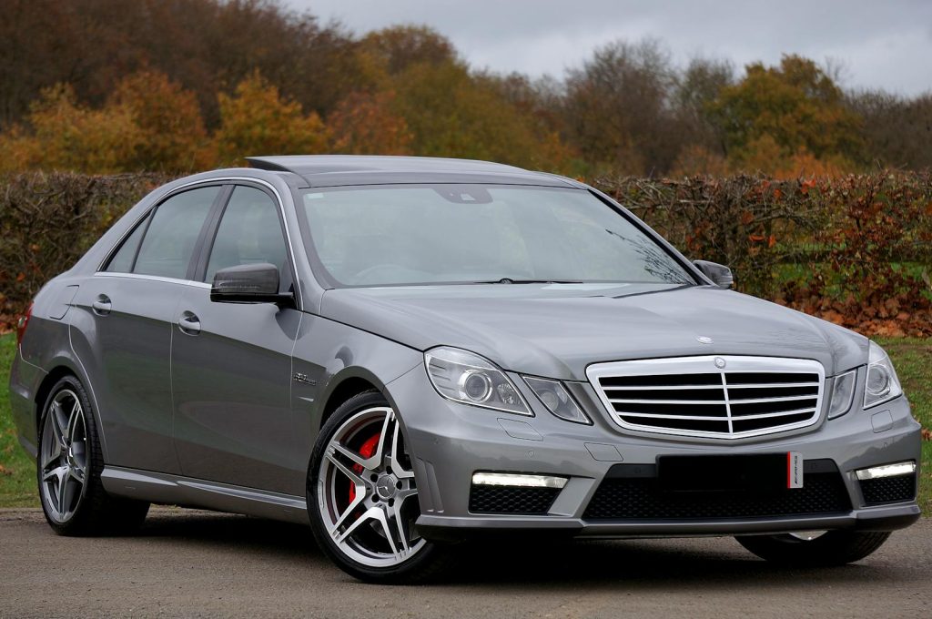A sleek luxury silver Mercedes Benz parked on a road outdoors in autumn.