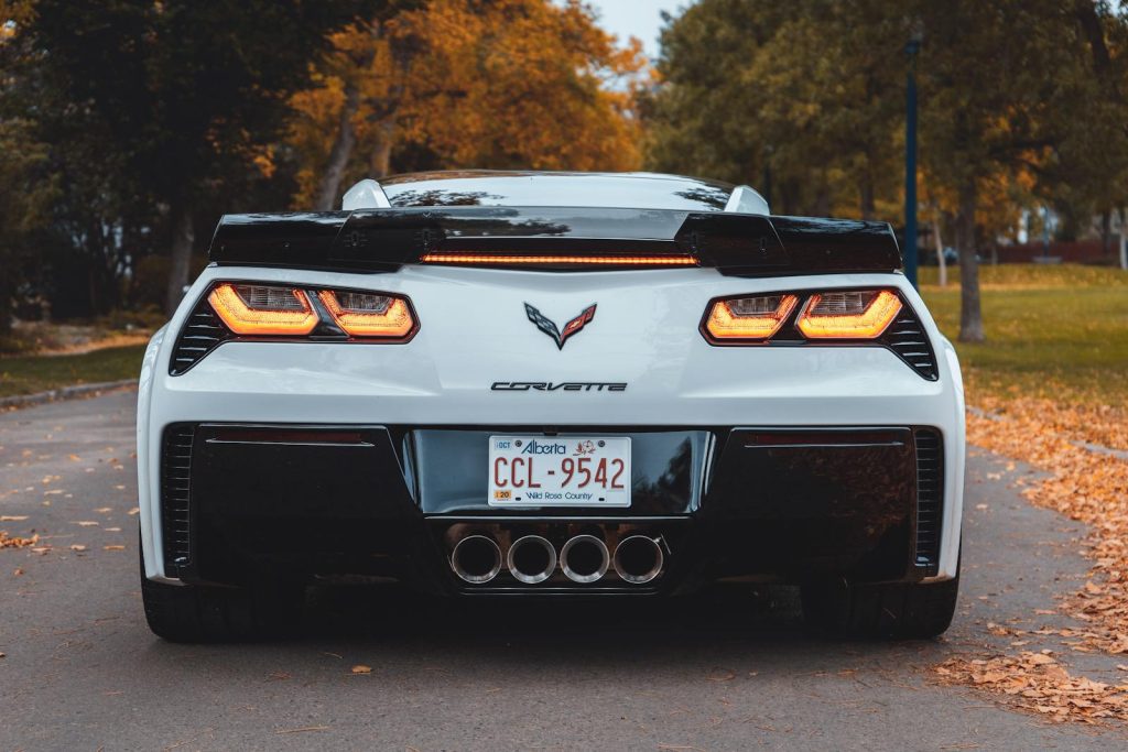 Luxury Corvette sports car on scenic road in Edmonton with autumn leaves.