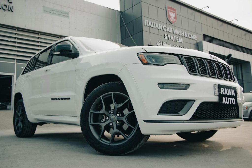 Low angle view of a white Jeep Grand Cherokee parked outside a car wash facility.
