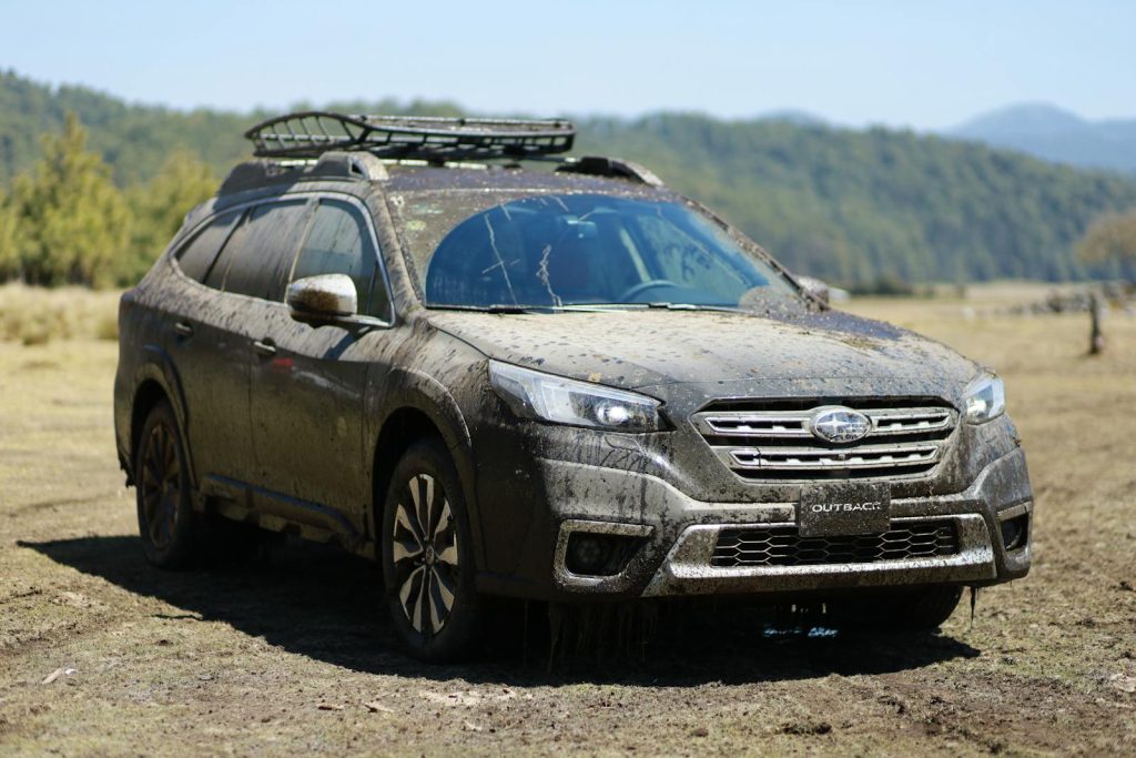A dirty SUV covered in mud, ready for adventure in a rural area.